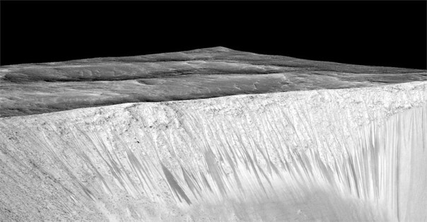 Dark narrow streaks called recurring slope lineae emanate out of the walls of Garni crater on Mars. The dark streaks here are up to few hundred meters in length. They are hypothesised to be formed by flow of briny liquid water on Mars.
